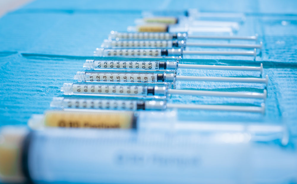 A row of syringes on a blue surface

Description automatically generated